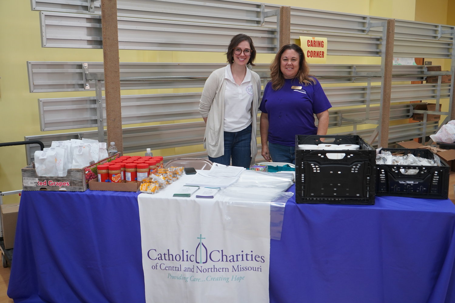 Ashley Wiskirchen, senior director of communications, and Lori Stoll, food programs coordinator, both for Catholic Charities of Central and Northern Missouri greet visitors to Project Homeless Connect on Sept. 30 in Jefferson City. Catholic Charities offered a selection of snacks and personal hygiene items, along with information about available services, to people who are homeless or near-homeless.